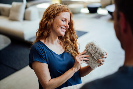 Smiling woman examining carpet sample at store
