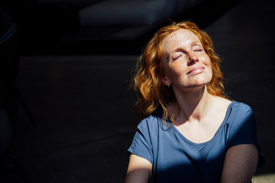 Redhead woman with sunlight over face
