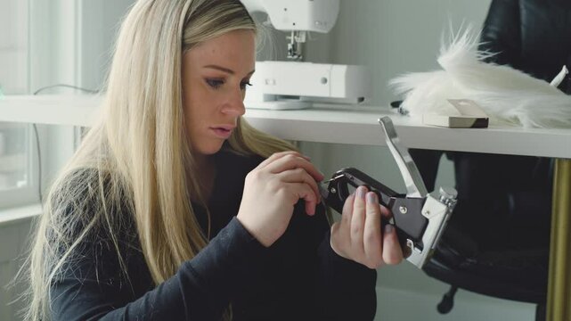 Woman loads staples into a staple gun at her home sewing desk