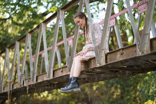 Happy woman sitting on bridge in front of trees