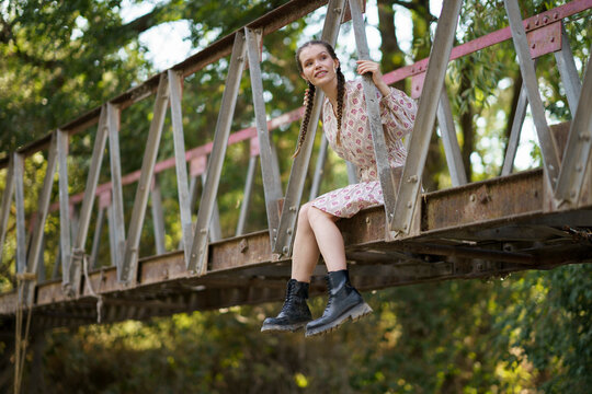 Happy woman sitting on bridge near trees
