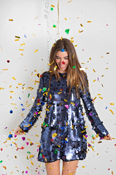Confetti falling on happy young woman in sequin dress against white background
