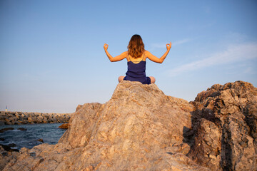 Woman in blue dress siting on rock in mudra positions