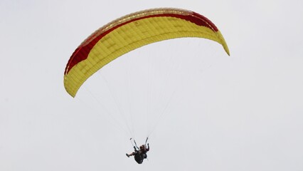 paragliding pilot flying in the blue sky with white clouds
