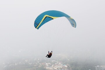 Paraglider flying high above village view and blue sky background