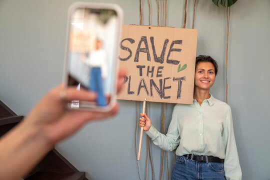 Hand of woman recording smiling activist holding placard