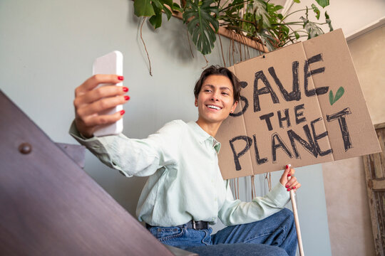 Happy activist taking selfie with environment placard