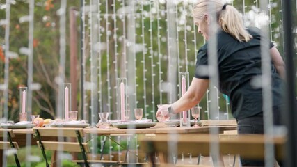 Wedding Planner Styling Reception Dinner Table With Candles And Glasses In Beautiful Outdoor Garden, 4K Slow Motion