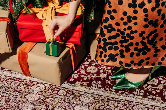 Fashionable woman opening gift on carpet at home
