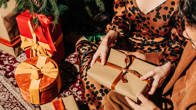 Couple sitting with gift boxes near Christmas tree - Powered by Adobe