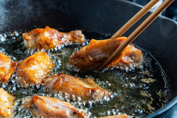 chicken wing fried until golden brown in bubbling hot vegetable oil, home cooking concept
