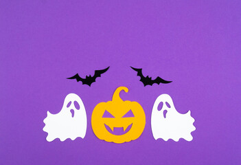 Fototapeta premium Colorful Halloween decorations featuring ghosts and a pumpkin against a vibrant purple background