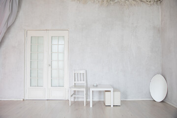 table, chair and mirror in the interior of an empty white room