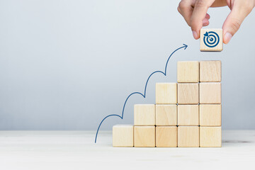 Wooden cubes stacking as step stair with arrow up and target icon. Ladder of success in business...