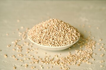 A ceramic plate filled with pearl barley on a light surface.