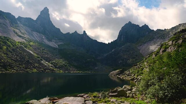 Ergaki, Khakassia, a mountain lake, rocks and clouds are floating around on a timelapse