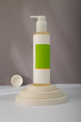 White dispenser bottle mockup on concrete round stairs stand, grey background. Unbranded beauty container, blank green label template. Copy space