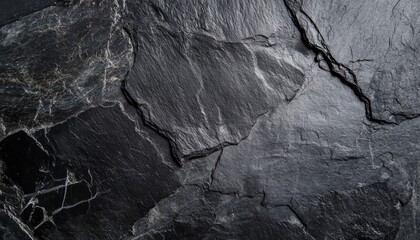 Fototapeta premium Close-up of dark, natural stone texture with visible cracks and veins, perfect for backgrounds or textures.