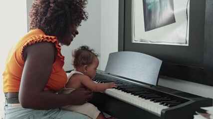 African mother teaching her baby girl to play piano