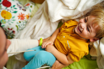 A joyful child laughs as his father tickles him on the bed, creating a fun and heartwarming family...