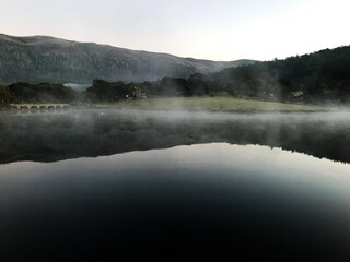 fog over the lake with the reflections of the mountains on the calm water