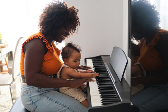 African mother teaching her baby girl to play piano