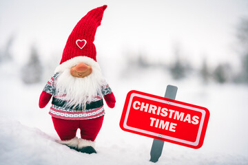 Santa claus outside in snowy winter landscape. Red sign with the text christmas time written.