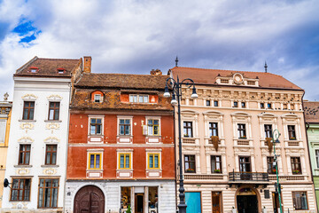 Fototapeta premium Brasov's historic Romanian architecture. In Brasov, historic structures display unique Romanian architectural styles beneath a cloudy sky, reflecting the city's rich heritage.