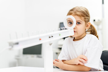 A little girl enjoys an engaging vision game on state-of-the-art ophthalmic equipment. The...
