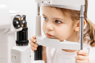 In a modern ophthalmology clinic, an ophthalmologist checks a little girl's vision using a...