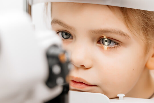 In a modern ophthalmology clinic, an ophthalmologist checks a little girl's vision using a binocular slit lamp in close-up. An example of contemporary techniques for children's vision correction.