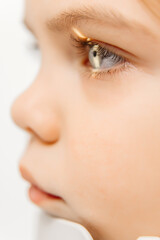 Examination of a little girl's eyes in an ophthalmology clinic. A laser beam shines into the child's eye, highlighting modern vision correction techniques and care for children's eye health.