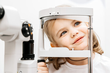 In a modern ophthalmology clinic, an ophthalmologist checks a little girl's vision using a...