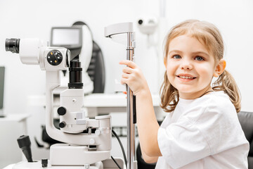 In a modern ophthalmology clinic, an ophthalmologist checks a little girl's vision using a binocular slit lamp in close-up. An example of contemporary techniques for children's vision correction.