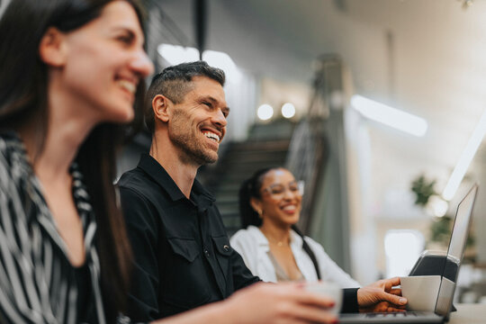 Happy male business professional with female coworkers working at office