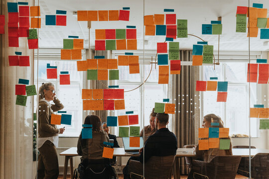 Business professionals in meeting room seen through glass wall of adhesive notes