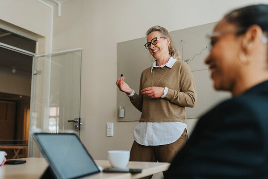 Happy businesswoman discussing with colleagues in meeting room