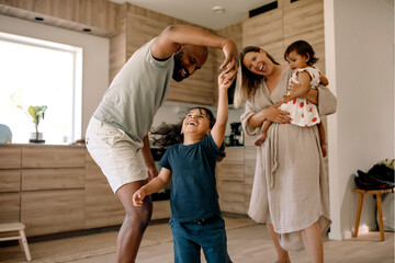 Cheerful family spending leisure time dancing in kitchen at home