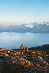 Couple man and woman enjoying mountains and fjord landscape, active family adventure vacations - friends hiking with backpacks in Norway together exploring Lyngen Alps, healthy lifestyle trip outdoor