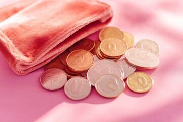 A soft pink wallet spills coins onto the surface. The warm light enhances their shine. Perfect for financial or lifestyle themes. Capture the moment with this vibrant scene. Generative AI