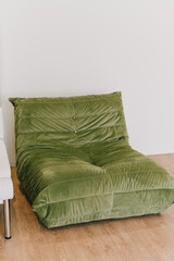 Cozy green lounge chair with soft, plush texture, perfect for relaxation in modern living space. Its unique design adds touch of comfort and style to any room