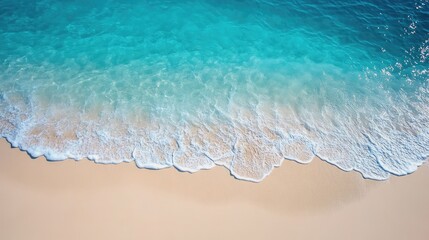 an empty beach from a top view, with untouched sand and clear, tranquil waters gently lapping at the shore.