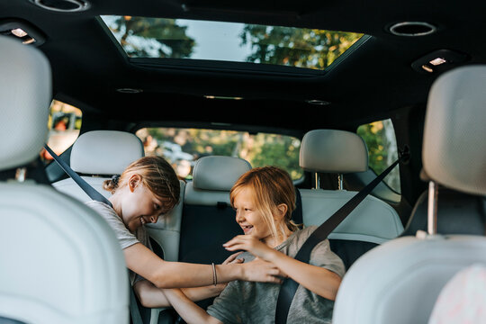 Playful male siblings tickling each other while sitting in car during road trip