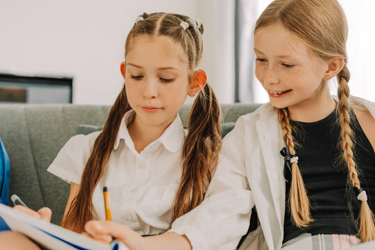 Two schoolgirls doing homework together and helping each other