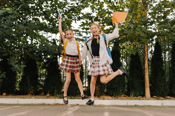 Two happy schoolgirls jumping with joy on the first day of school