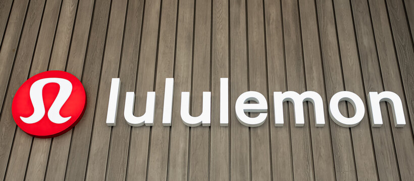 The Lululemon store corporate logo in red and white on a wooden background, at Vancouver City Shopping Center
