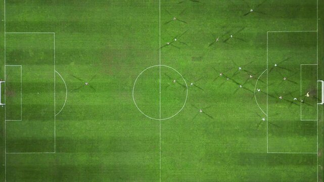 Drone footage of a football match from a top-down view, showcasing players on the pitch during an intense play near the goal, offering a unique aerial perspective