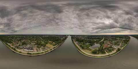 A360-degree panoramic view of a cloudy sky over a river flanked by buildings, roads, and greenery.