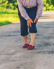 Old woman has knee pain in nature. Selective focus.