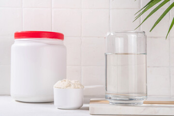 Collagen protein powder with glass of water on white kitchen table